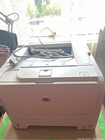 Front angled view of the HP LaserJet Pro P2935n printer on a surface with cables on top.