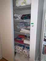 Photo of the cupboard fully stocked with linens, towels, and toilet paper on shelves