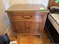 Front view of wood nightstand with closed drawer and cabinet, glass top visible.
