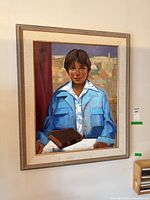 Full view of the framed portrait painting on board of a young boy in a blue jacket, holding a book.