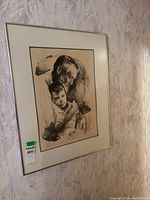 Framed signed lithograph artwork showing an elderly man and young boy, hung on a floral wallpapered wall.