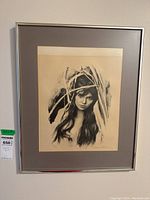 Full view of framed print on wall showing black and white image of a young woman surrounded by branches.