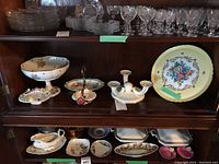 Overview of serving ware items including cake stands, bowls, and plates on wooden shelves.