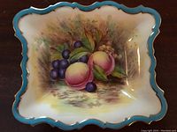 Top view of the rectangular candy bowl showing the hand-painted fruit design and turquoise scalloped edge with gold trim.