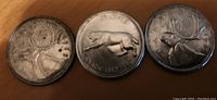 Photo of three Canadian quarters, two 1968 and one 1967, silver content evident, coins show wear and tarnish.