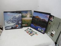 Three hardcover Canada Post annual stamp collection books from 1996, 1997, and 1998 with scenic Canadian landscapes on the covers, displayed standing side by side with extra loose stamps in front.