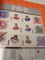 Close-up photo of NHL All-Stars themed stamps featured inside a stamp collection album. Stamps show Canadian hockey players and logos with colorful illustrated backgrounds.
