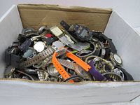 Wide view of shoe box full of mixed broken wristwatches mostly with metal bands and few plastic ones