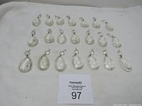 Overview of 21 clear glass chandelier prisms arranged in rows showing size and condition.