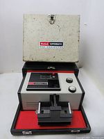 Front view of Kodak Supermatic 500 Slide Projector inside the open carrying case showing the projector body and case top labeled Kodak Supermatic 500 Projector.