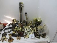 Various vintage lamp components in brass and metal, including lamp holders, arms, sockets, rings, and plastic lampshade parts displayed on white surface.