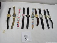 Full lot of 10 vintage men's wristwatches laid out in a row on a white cloth background.