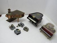 Overview of lot showing two piano-shaped music boxes and four metal music box mechanisms.