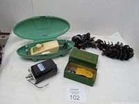 Photo showing vintage Singer buttonholer in open green case, new black motor, green box of attachments, and rings of black fashion disks.