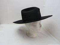 Side angle view of the black cowboy hat on a mannequin head, showing the shape and wide brim.