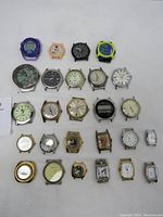 Full lot view of 26 vintage wristwatch faces and mechanical parts without straps, arranged on white background showing varied styles and conditions.