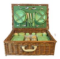 Open wicker picnic basket showing interior contents including green plates, cutlery, metal and plastic containers, and thermoses.