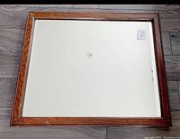 Front view of rectangular beveled mirror with oak frame placed on floor, shows mirror surface and frame condition.