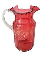 Front side view of cranberry pitcher showing applied handle, ruffled edge, and gold decoration.