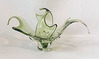 Front angle of green Chalet art glass bowl showing its elongated curved extensions and clear base with green coloration.