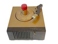 Front angle showing the yellow and brown Bakelite casing with red spindle and tonearm. Visible speaker grille on left side and RCA Victor logo on front right corner.
