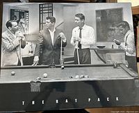 Black and white glossy board print featuring The Rat Pack (Frank Sinatra, Dean Martin, Peter Lawford, Sammy Davis Jr.) around a pool table with text 'THE RAT PACK' beneath the image.