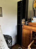 Two tall black CD/DVD towers standing side by side against a wall, showing their slim design and adjustable shelf holes.