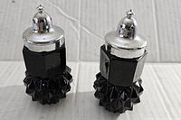 Two black Indiana Glass Tiara salt and pepper shakers with textured bottom halves and smooth upper halves, silver-tone metal shaker tops.