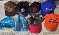 Photo showing 8 caps including Detroit Tigers, Captain America, Avengers, YAYA, knit hats, Bud Light knit beanie, pirate skull, and orange Dial Champs cap