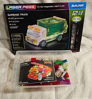 Front view of Laser Pegs Garbage Truck Builder set box, showing model of a green garbage truck with 12 LED lights, age 8-14 recommended, 180 pieces included.