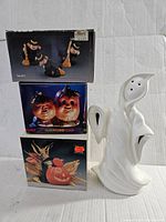Image showing white ceramic ghost figurine and three collectible Halloween decoration boxes.