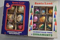 Two original boxes of vintage Santa Land Christmas tree ornaments, one containing 6 ornaments and the other 9 ornaments, showing colorful packaging and window display.