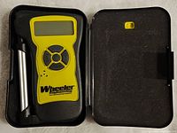 Wheeler Professional Trigger Gauge in open black foam-lined case showing device with digital screen and control buttons along with metal trigger arm.