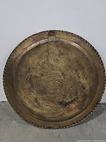 Front view of circular solid brass wall hanging with engraved Aztec calendar design and central face motif. Shows wear and patina.