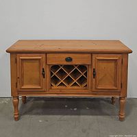 Front view of oak buffet server showing two paneled doors, central drawer with handle, and lattice wine storage.