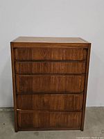 Front view of mid-century dresser showing closed drawers and wood grain finish.