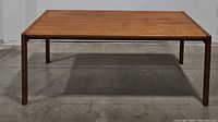 Front view of mid-century wooden dining table showing wood grain finish and square legs