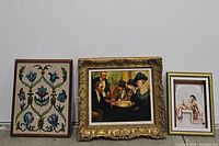 Three framed art pieces side by side: needlepoint floral, classic painting of card players, and 3D print of woman.