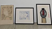 Three framed prints side-by-side on floor showing diverse modern art styles described