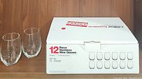 Two clear glass stemless wine glasses shown next to the original white box for a 12-piece stemless wine glasses set by Century Eastern.
