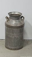 Front view of vintage metal milk jug showing inscription 'Farmers Co-Op Dairy Hazleton PA' and carrying handles.