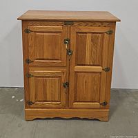 Front view of the closed mission style solid wood cabinet with three doors and metal hinges and locks.