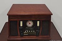 Front view of wooden music center showing AM/FM analog radio dial, speakers, and control buttons.