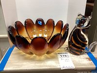 Photo showing the amber scalloped art glass bowl and glass cat figurine side by side, highlighting colors and shapes