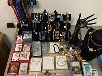 Full overview of costume jewelry including boxes with earrings, bracelets on display bars, and jewelry hands with necklaces.
