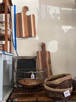 Overview of cutting boards on wall, wooden bowl, wire basket, wicker baskets stacked
