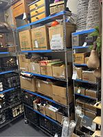 Full view of 6-tier metal shelving unit filled with various boxed and loose items, showing shelving and wheels.
