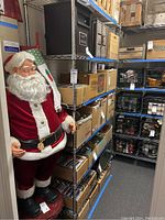 Six-tier metal wire shelving unit loaded with boxes and other items, next to a decorative Santa figure. Shelf items not included.