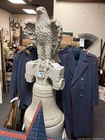 Full view of entire statue on display showing eagle, support beam and bell base