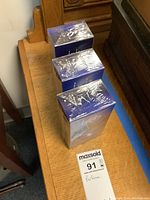 Three sealed boxes of Inis Moonlight Eau de Parfum, 100 ml, in original plastic wrap on wooden surface with lot tag visible.